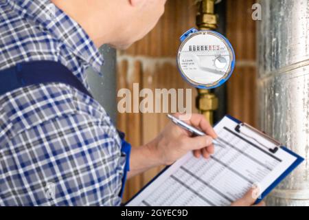 Technician With Clipboard Reading Water Meter Or Counter Stock Photo