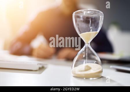 Hourglass On Desk. Running Late With Invoice Or Bill Stock Photo
