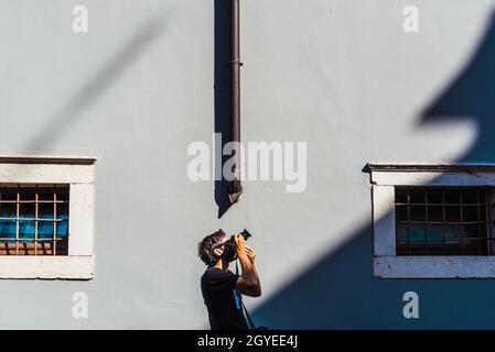 A young amateur photographer takes shots of architectural motifs on a sunny day in a minimalist setting with a simple background. Stock Photo
