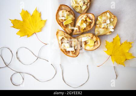 Baked pears with brie cheese and nuts against the background of autumn yellow leaves. Stock Photo