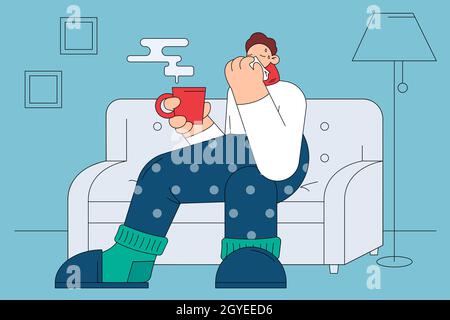 Flu, infection, getting cold concept. Sad ill man cartoon character in warm socks sweater and scarf sitting on sofa with hot drink, sneezing and feeli Stock Photo