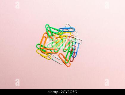 Office paper clips isolated on colored background. Pink, red, blue, green, orange colorful Plastic paperclips documents staple attach tools. Stock Photo