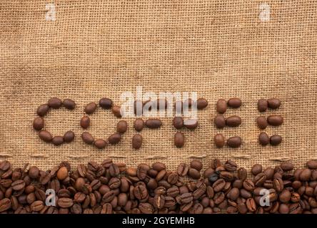 The word coffee made from coffee beans on sackcloth next to coffee beans Stock Photo