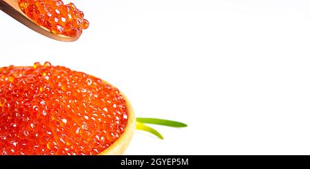 Red caviar in a wooden cup on a white background with a spoon and green onions. A large pile of bright caviar. Fresh delicious caviar. Isolated. A pla Stock Photo