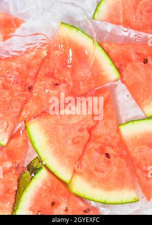 Close-up fresh slices of red melon on white background. Slices of melon in sparkling water on white background, close-up. Copy space. Stock Photo