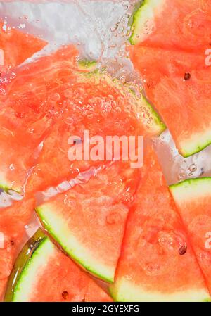 Close-up fresh slices of red melon on white background. Slices of melon in sparkling water on white background, close-up. Copy space. Stock Photo