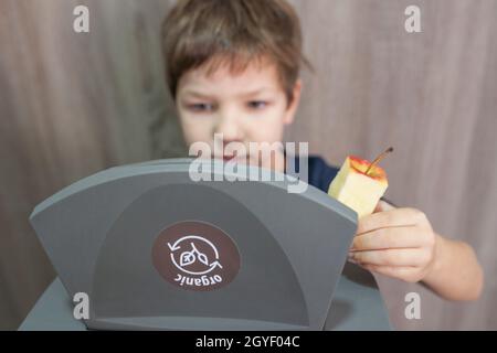 Child boy throwing apple core to waste bin for organic at home. Education about Waste Segregation concept Stock Photo