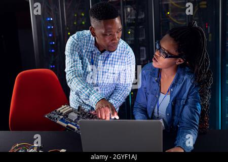 African american computer technicians using laptop working in server room Stock Photo