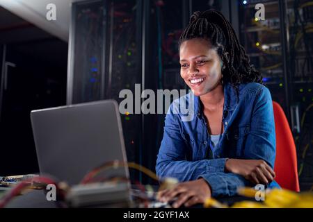 African american female computer technician using laptop working in server room Stock Photo