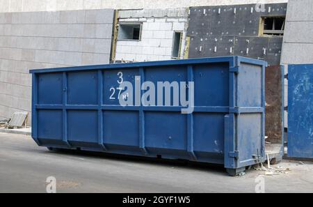 Metal durable blue industrial trash bin for outdoor trash at construction site. Large waste basket for household or industrial waste. A pile of waste Stock Photo