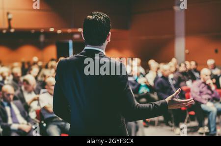 Speaker at Business Conference with Public Presentations. Audience at the conference hall. Entrepreneurship club. Rear view. Panoramic composition. Ba Stock Photo