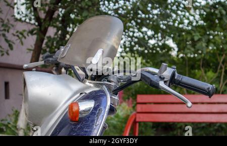 Vintage scooter or mini motorcycle stands outdoors. A popular form of transport. The steering wheel of an old blue moped with a brown seat Stock Photo