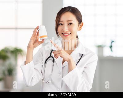 Smiling doctor pointing jar of pills. Stock Photo