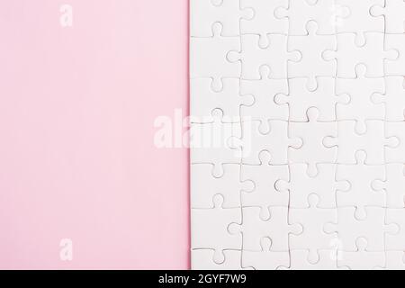 Top view flat lay of paper plain white jigsaw puzzle game texture on a pink background, quiz calculation concept Stock Photo