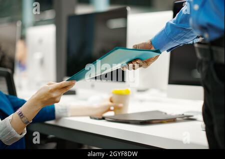 Two managers exchange documents in IT office. Professional teamwork and planning, group brainstorming, modern company interior on background Stock Photo