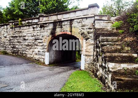 Small road going under stone tunnel with stone steps to the top Stock Photo
