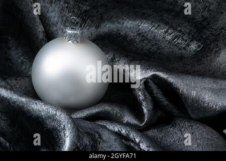 Christmas bauble decoration on silver background with copy space for text. New Year greeting card. Shiny Christmas card with Christmas ball on silver Stock Photo