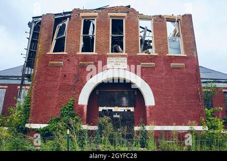 Small abandoned high school of red brick with broken windows and no trespassing signs Stock Photo