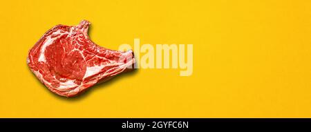 Raw beef prime rib isolated on yellow background. Top view. Horizontal banner Stock Photo