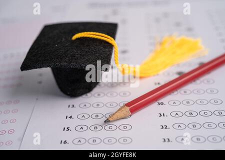 Graduation gap hat and pencil on answer sheet background, Education study testing learning teach concept. Stock Photo