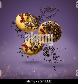 Flying donuts. Doughnuts with sprinkles on purple background Stock Photo