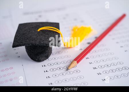 Graduation gap hat and pencil on answer sheet background, Education study testing learning teach concept. Stock Photo