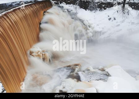 Water pours over the dam and icy rocks in the mouth of Vantaa River at the Vanhankaupunginkoski rapids (Vanhankaupunginkosken putous) extremely cold w Stock Photo