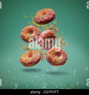 Flying sweet donuts with sprinkels on green background Stock Photo