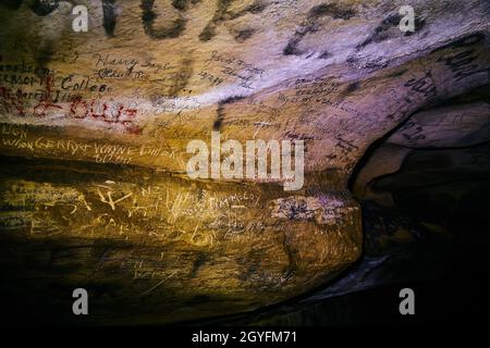 Names carved into cave wall surrounded in darkness Stock Photo