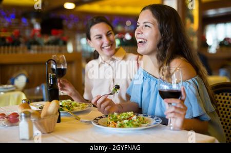 Two girls are discussing something fun at a table in restaurant Stock Photo