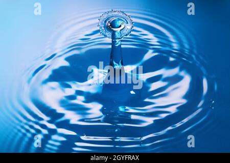 Two water drops crashing and creating ripples on clean blue water Stock Photo