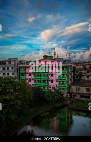 A building on the lakeside and some trees with cloudy blue sky. Agrabad, Chittagong, Bangladesh. Stock Photo