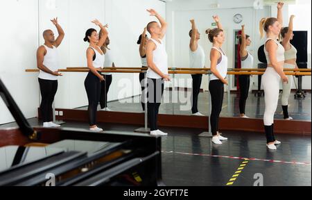 Dancers doing exercises on stretching ballet barre Stock Photo