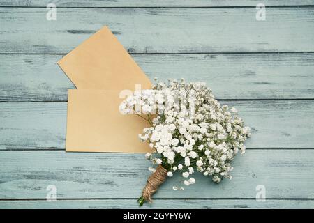 Beautiful gypsophila flowers and envelopes on color wooden background Stock Photo