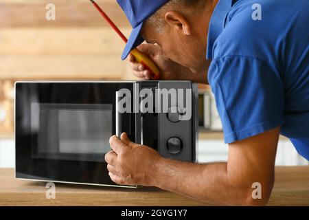 Male worker repairing microwave oven in kitchen Stock Photo