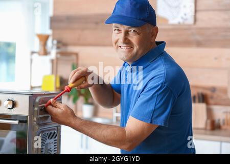 Male worker repairing microwave oven in kitchen Stock Photo