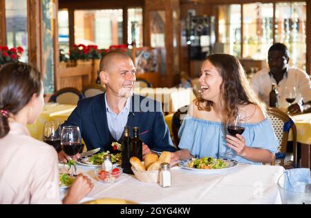Two cheerful couples having dinner and nice talking Stock Photo