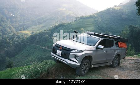 Traveling by pickup truck and camping with rooftop tent. Mitsubishi L200 Triton is parked on the mountain with terraces. Amazing nature landscape Stock Photo