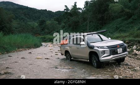 Traveling by pickup truck and camping with rooftop tent. Mitsubishi L200 Triton is parked on the stream in the forest. Amazing nature landscape Stock Photo