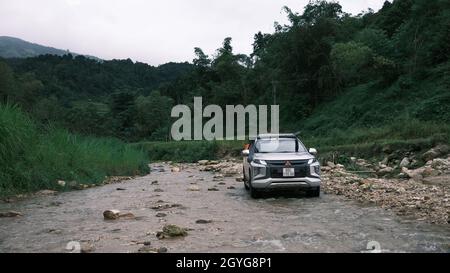 Traveling by pickup truck and camping with rooftop tent. Mitsubishi L200 Triton is parked on the stream in the forest. Amazing nature landscape Stock Photo