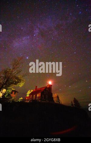 Milky Way over harbor lighthouse with light on Stock Photo