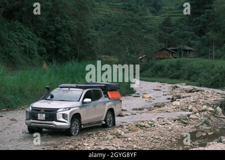 Traveling by pickup truck and camping with rooftop tent. Mitsubishi L200 Triton is parked on the stream in the forest. Amazing nature landscape Stock Photo