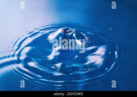 Clean blue water broken by ripples from two water drops hitting in air Stock Photo