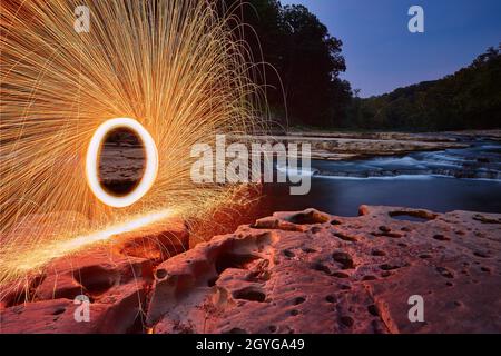 Portal of yellow sparks against craggy stone and rock in front of waterfalls at Cataract Falls Stock Photo