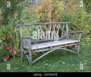Rustic wooden bench in an autumn garden at the Reader Rock Garden Historic Park, a designated provincial and national historic site in Calgary, Stock Photo