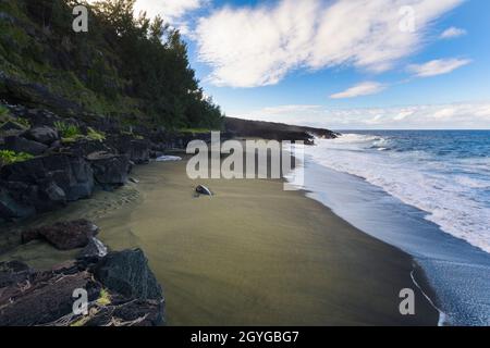 Wild beach with volcanic rocks at Reunion Island with a blue sky Stock Photo