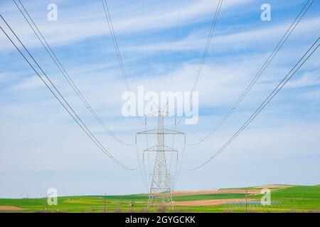Electricity Pylon Blue sky. Large Pylon shot from distance against brilliant blue sky with cables running left and right Stock Photo