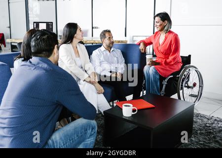 Mexican transgender woman in a wheelchair talking with group of friends in Latin America Stock Photo