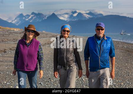 Vacationers walk on the spit with a view of KACHEMAK BAY and the Chugach mountain range and Kachemak Bay State Park - HOMER, ALASKA Stock Photo