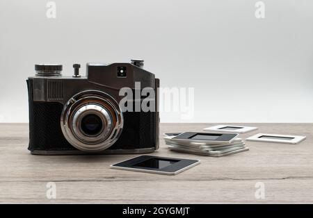 Retro photo camera with slides on wooden table. Stock Photo